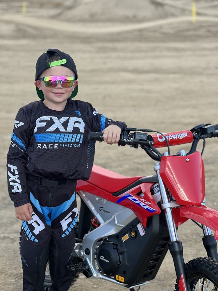 RevZilla tester Onyx Allen standing next to a Honda CRF-E2 mini dirt bike.