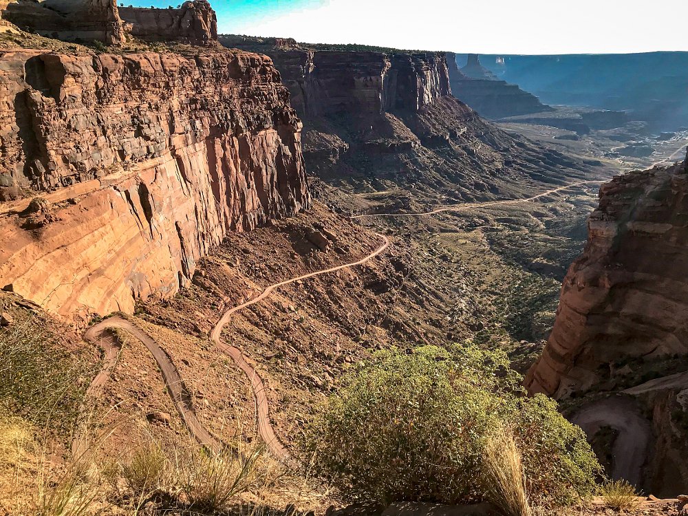 view from mountain top of dirt road through canyons