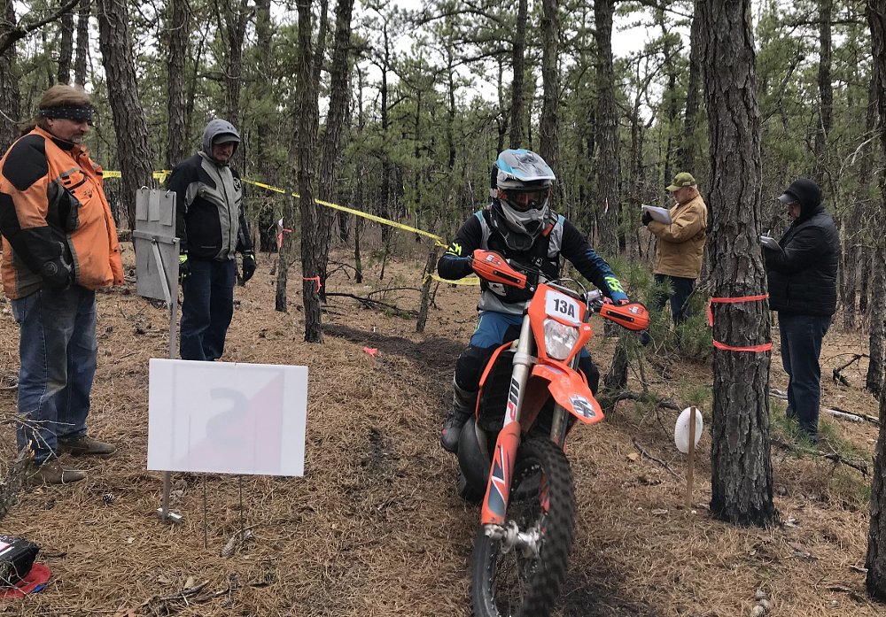 an enduro race bike passing a checkpoint in the woods