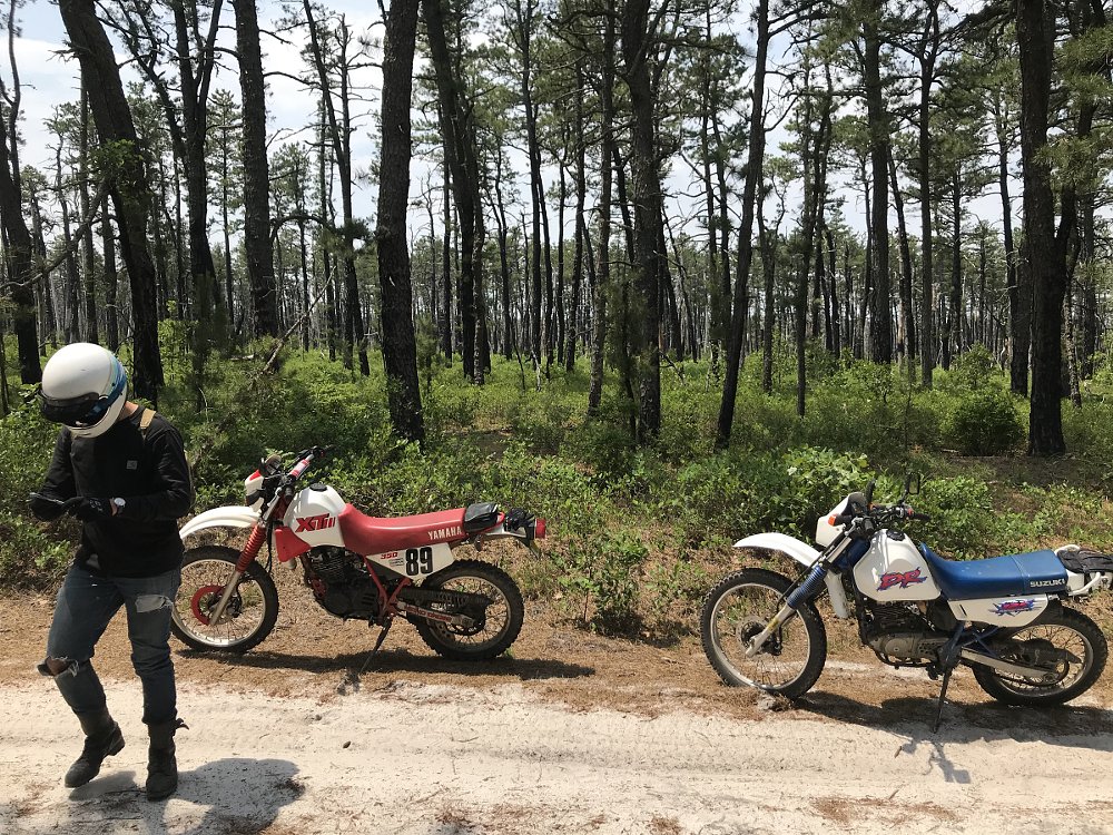 rider by two dirt bikes parked at the edge of the trail
