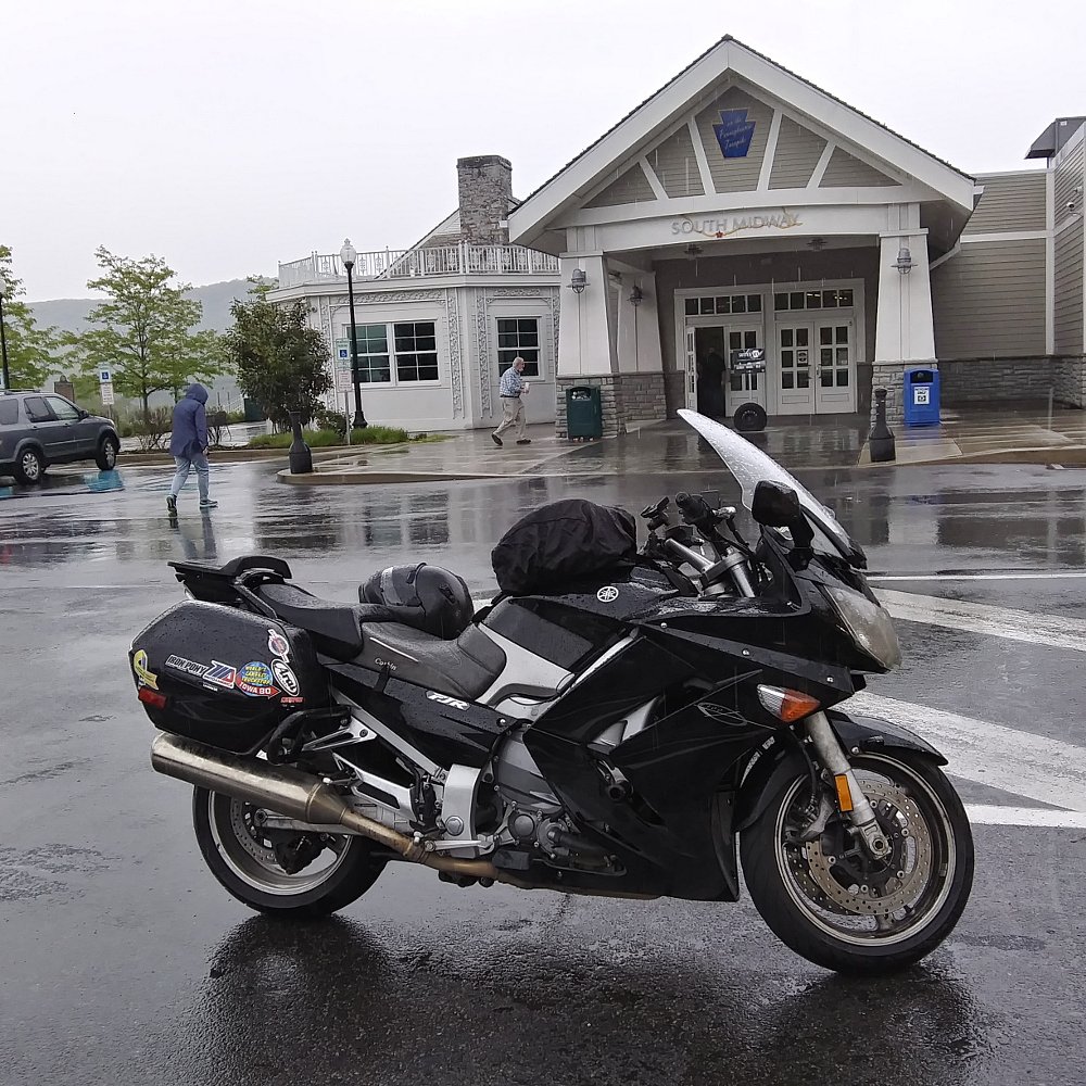 Motorcycle parked in the rain outside the Midway Service Plaza