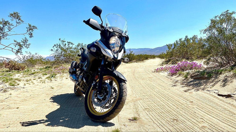 A photo of the V-strom 650 on a sandy dirt road in the desert