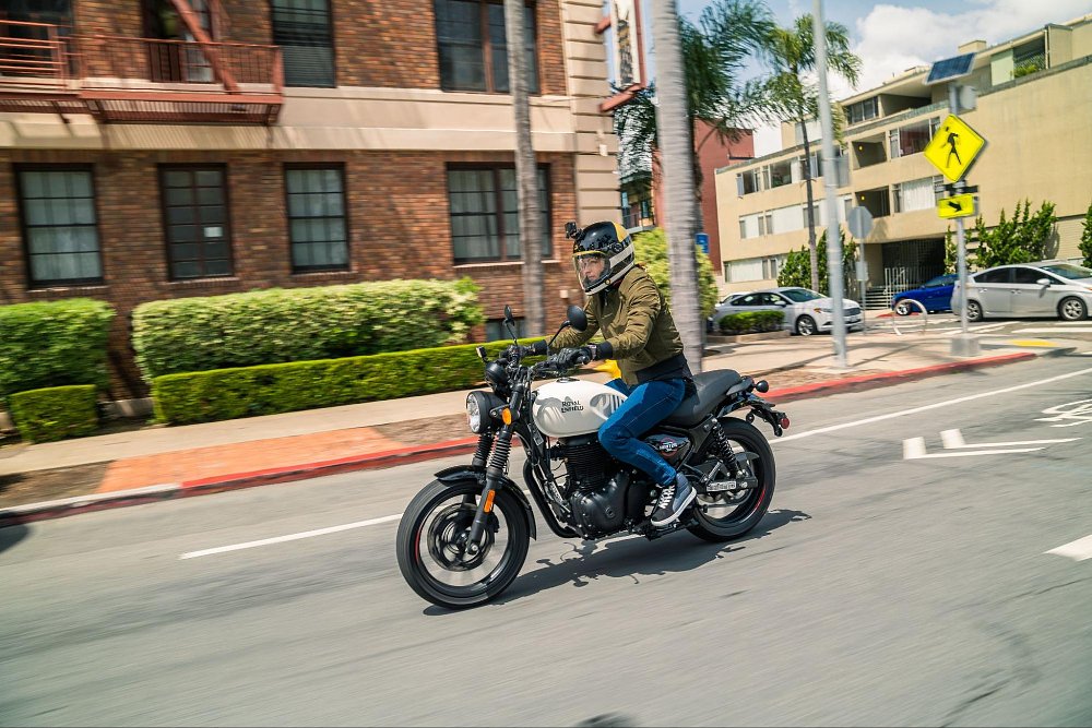 A female rider on the hunter 350 in a brick building city block