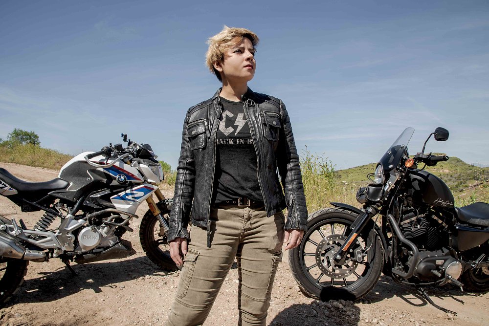 A photo of female rider Maja standing in front of her Harley cruiser and BMW adventure bikes
