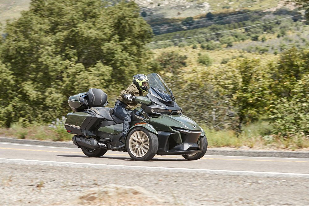 a photo of jen from the side view riding around a curve on the road on board the spyder rt