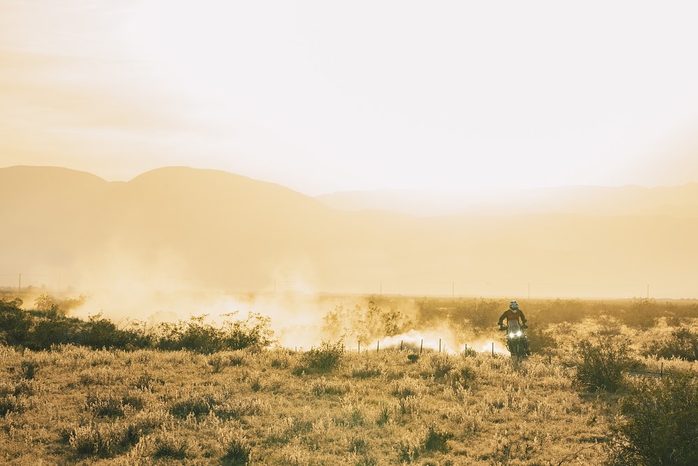 A CFMOTO Ibex 800 T riding across the desert kicking up a cloud of dust.