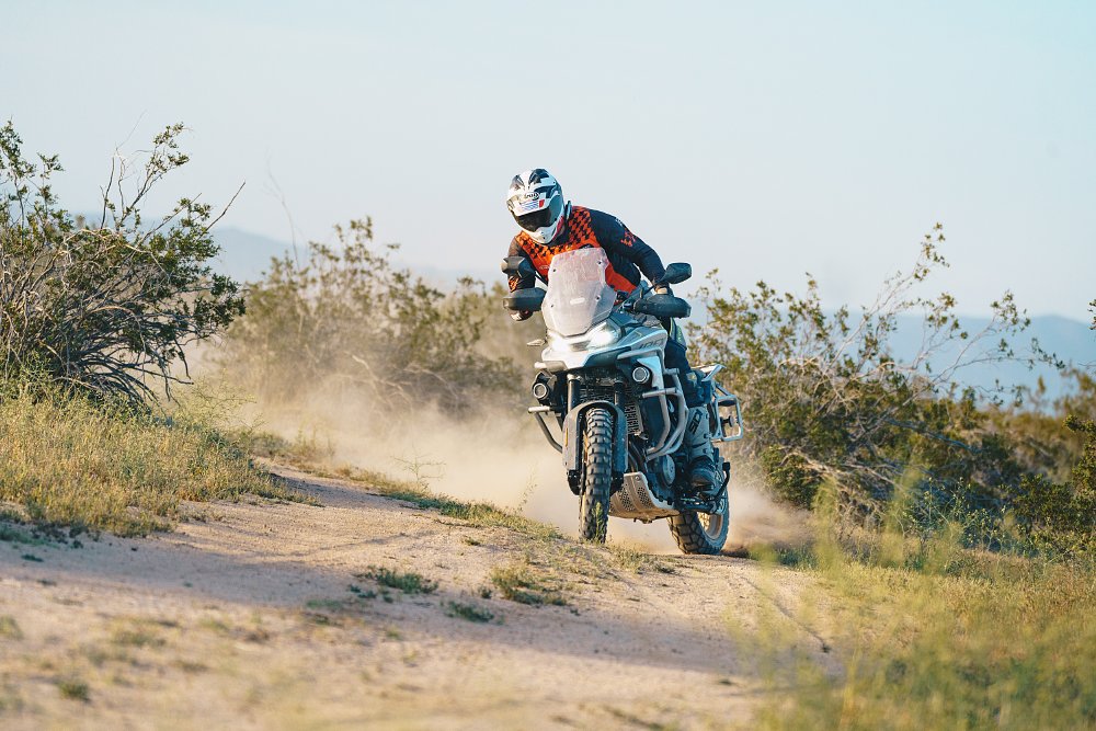 A CFMOTO Ibex 800 T sliding around a corner on a two-track dirt road.