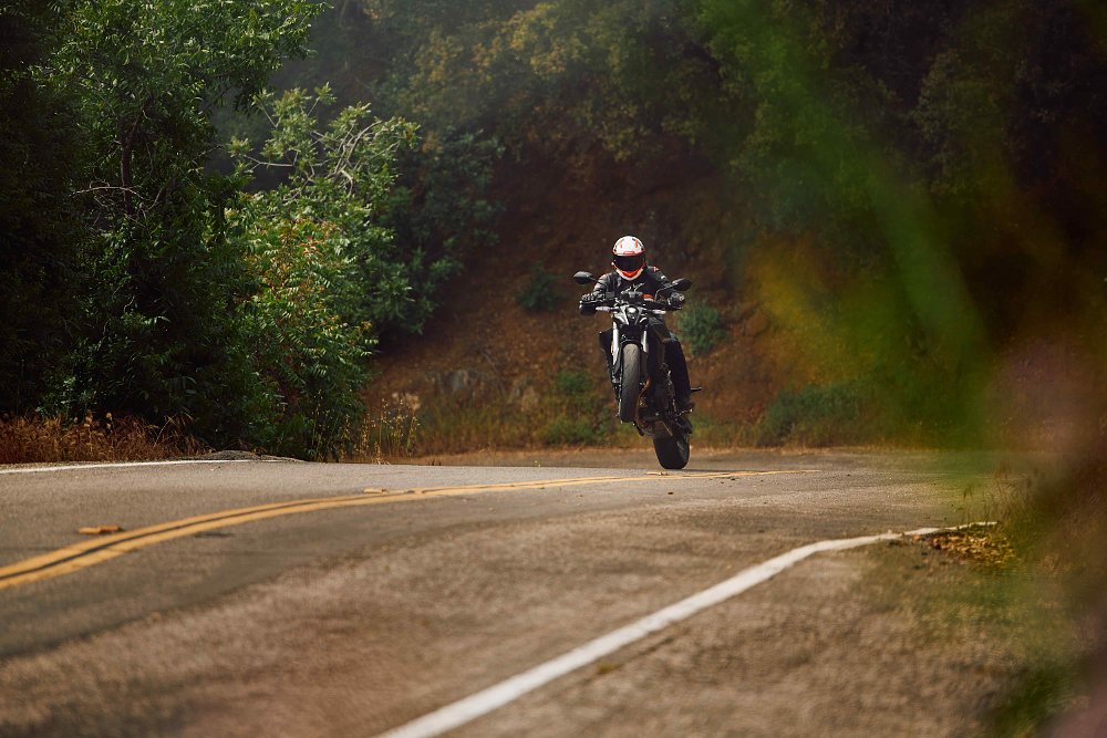 2023 Suzuki GSX-8S wheelying out of a corner on a mountain road.