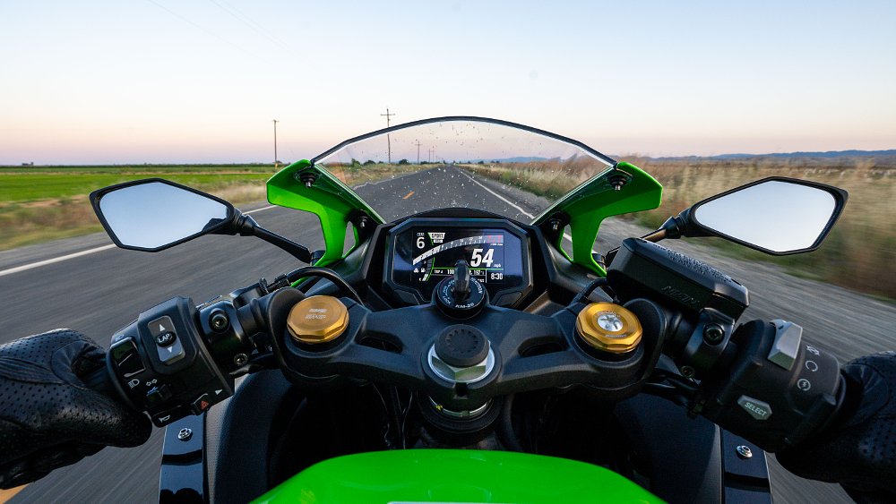 On board a 2023 Kawasaki ZX-4RR, looking forward through the windshield at a straight, country road at sunset.