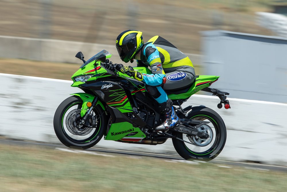2023 Kawasaki ZX-4RR speeding down a straightaway on a race track, shown in profile from the left.