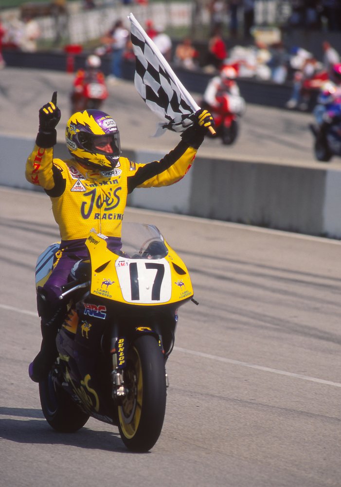 Miguel Duhamel celebrating a win by waving the checkered flag on his Honda CBR600F3 race bike