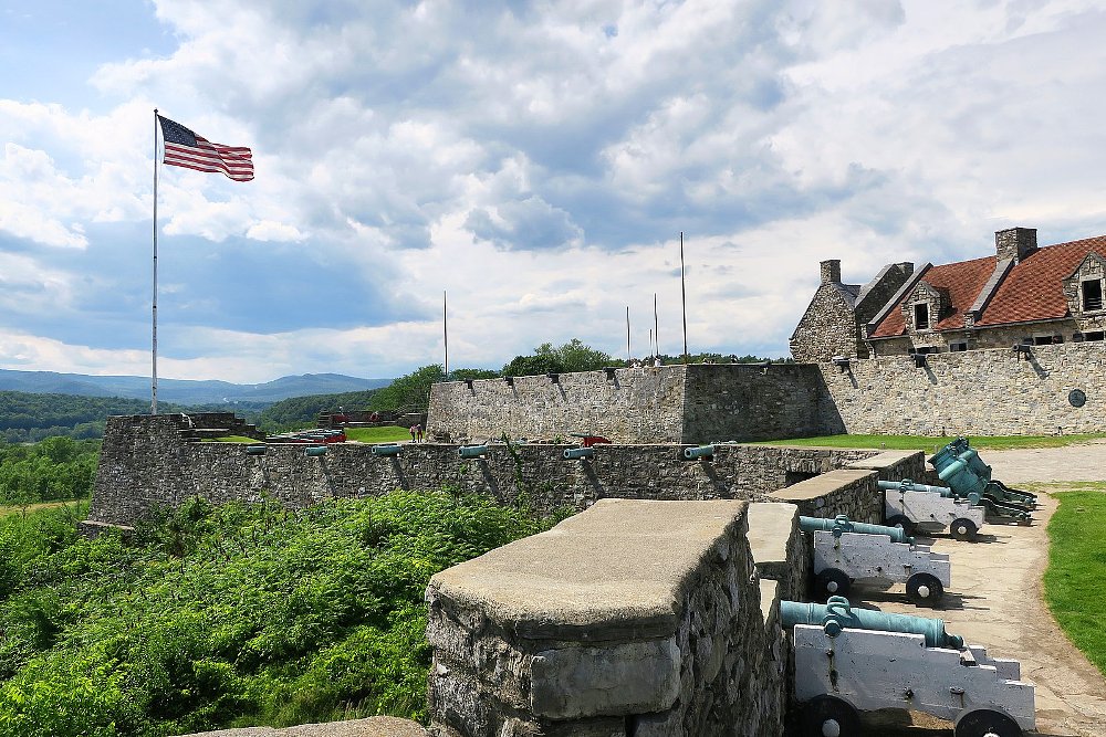 a photo of the fort and the cannons in place with american flag waving in blue skies