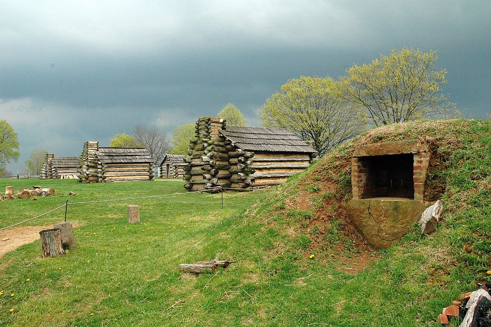 A photo of the log cabin style soldiers quarters in a misty Valley Forge meadow