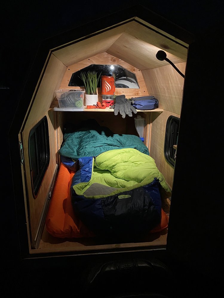 The interior of the Wing-ebago motorcycle motorhome at night, with sleeping bag and air mattress inside.