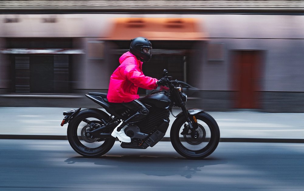Charlotte de Witte riding the LiveWire S2 Del Mar wearing bright vinyl clothing and white shoes
