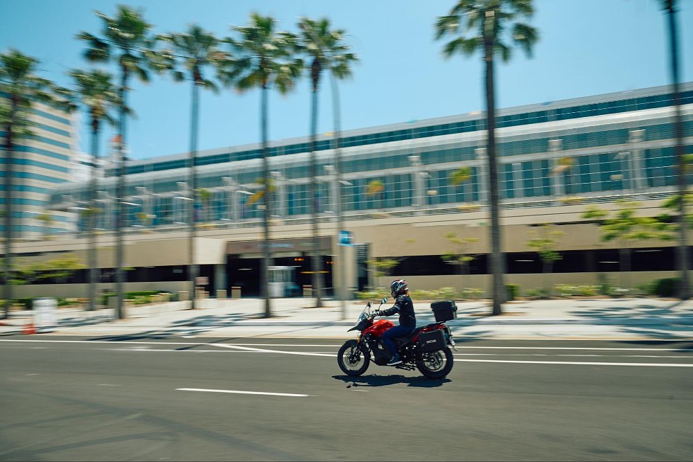 a far away view of the RX1E riding down a palm tree boulavrd with buildings