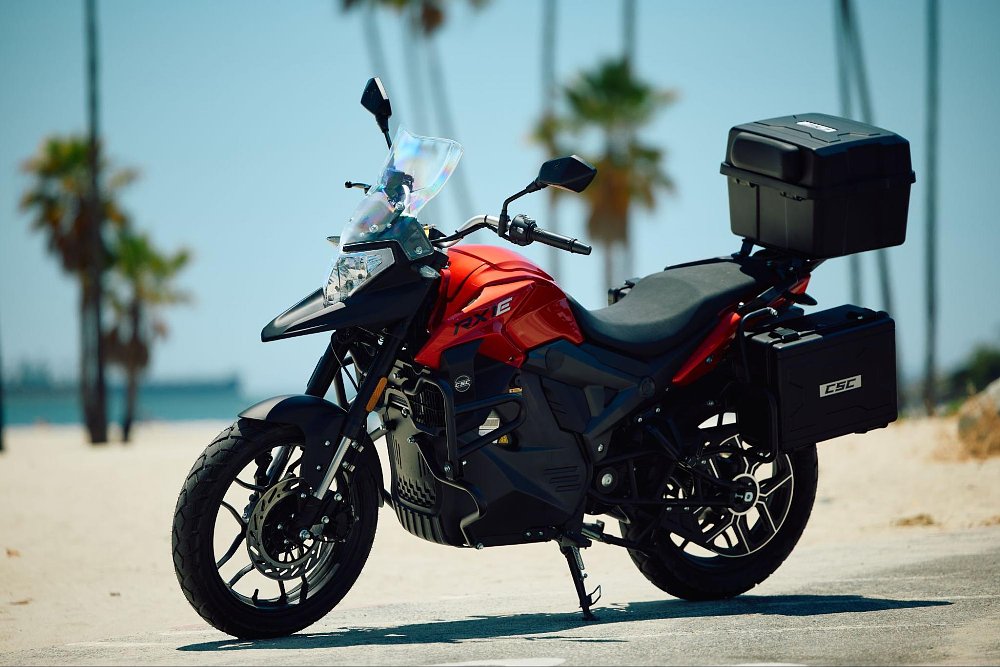 The CSC RX1E electric motorcycle in red paint parked in a beach parking lot