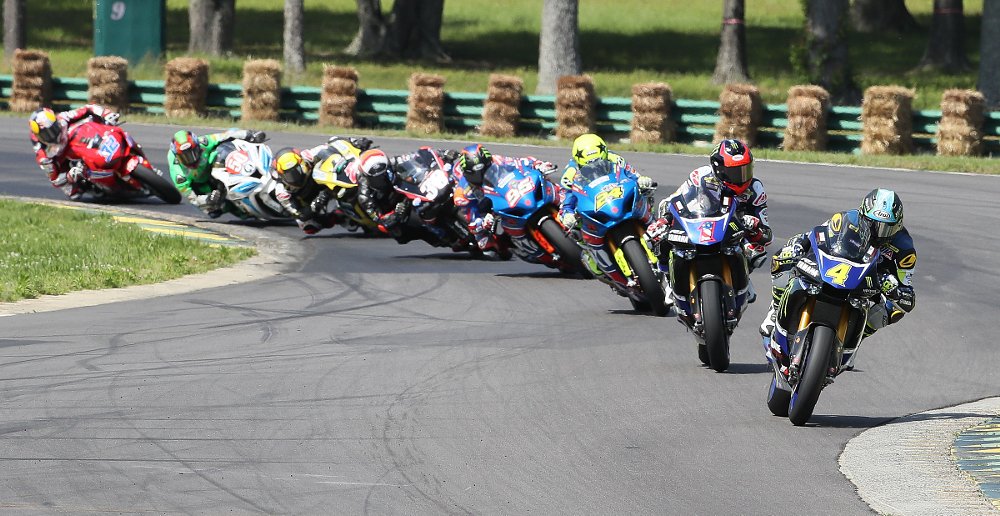 the bunched field at the beginning of a 2017 MotoAmerica Superbike race