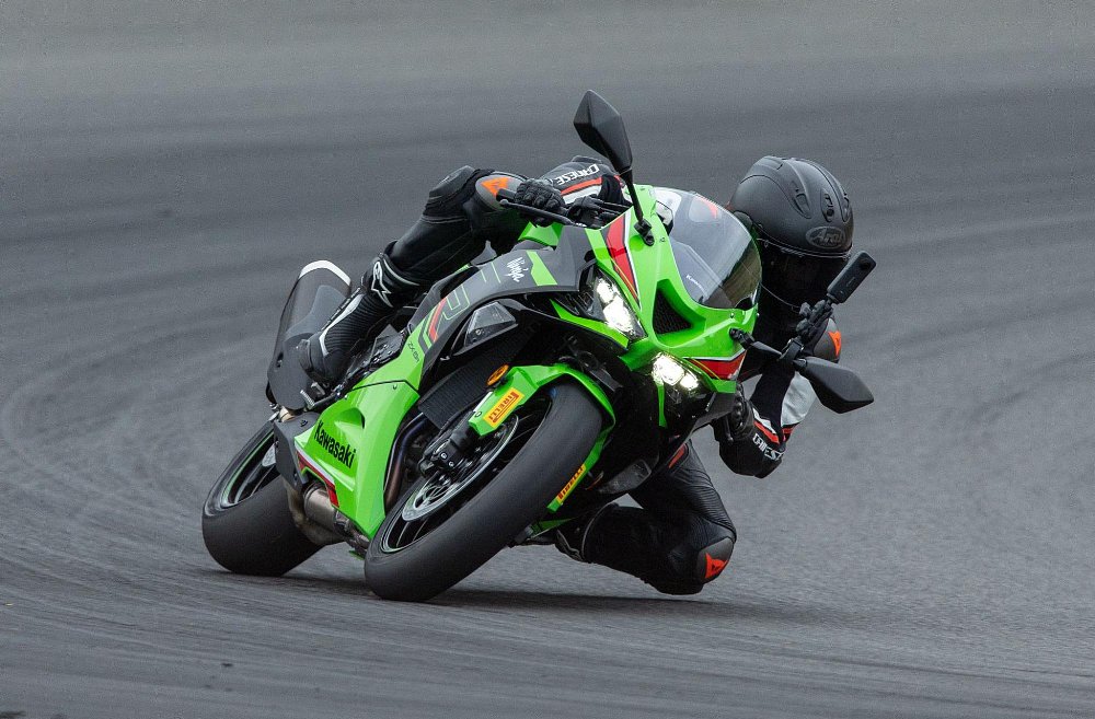A female rider pilots the 2024 kawasaki ninja zx-6r around the corner of an asphalt race track