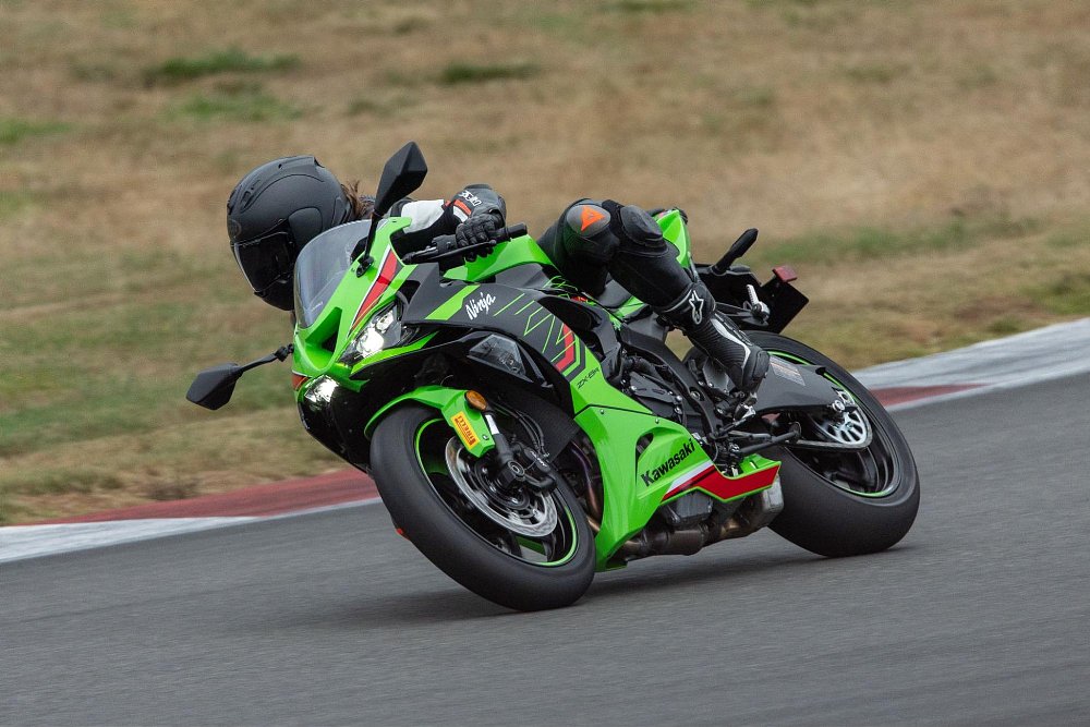 A female rider aggressively rides the zx-6r on the trace track fully leaned over in the corner