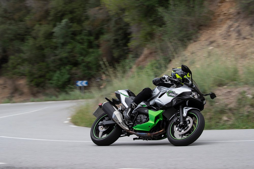 a female rider goes through a corner on a back country road on the ninja 7 hybrid