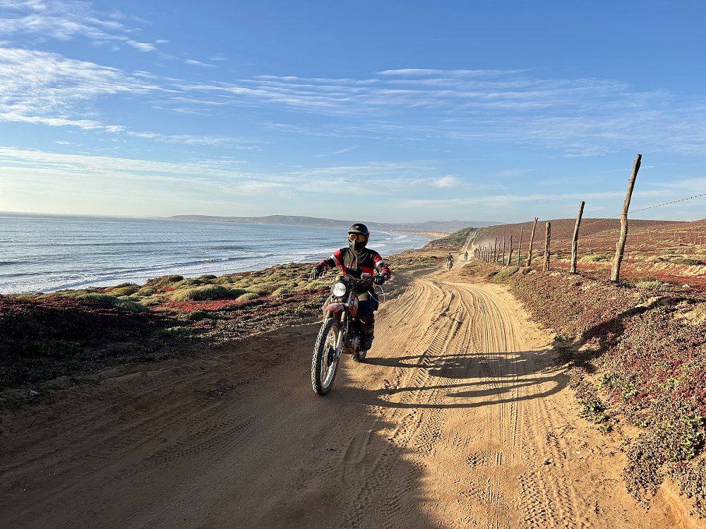 rider on a sandy dirt road in front of the ocean