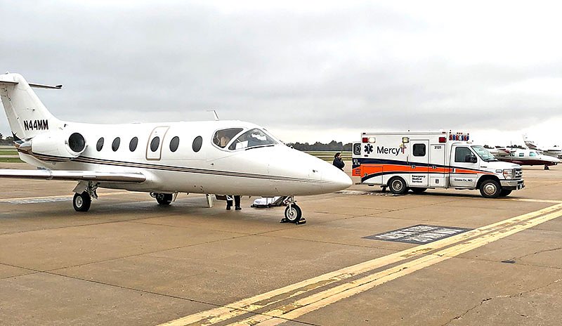 A private air plane with an ambulance parked next to it at an airport