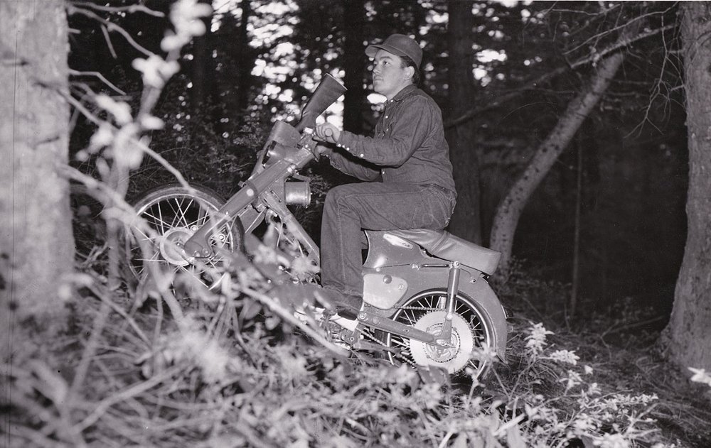 old black-and-white photo of Herb Uhl riding a Honda Trail bike in the woods