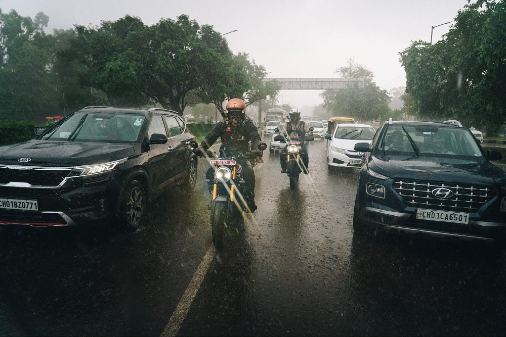 Two motorcycle rrders in city traffic in the pouring rain