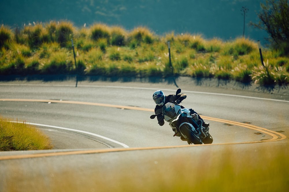 2023 Moto Guzzi V100 Mandello riding through a banked right-hand corner toward camera