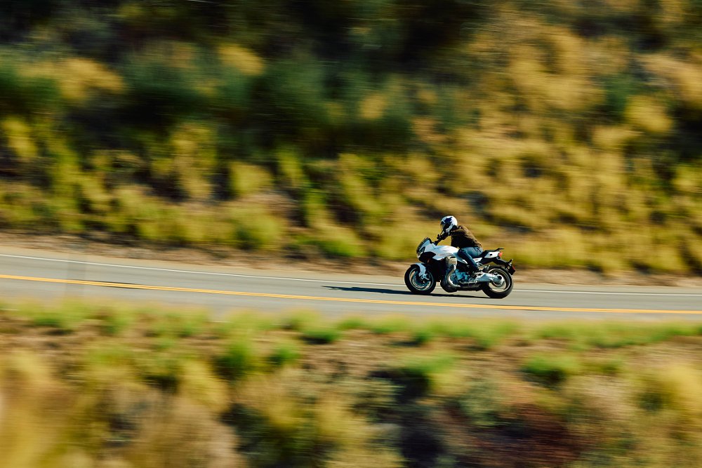 2023 Moto Guzzi V100 Mandello from the left side streaking along a mountain road