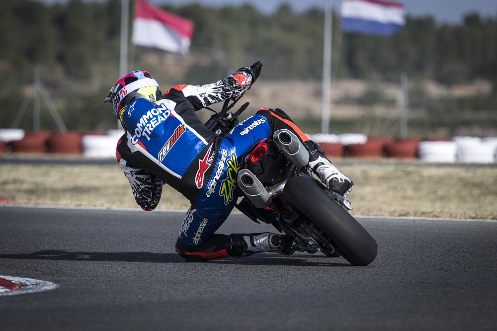 2024 Ducati Hypermotard 698 rear end, riding away from camera through a left-hand corner at a race track.