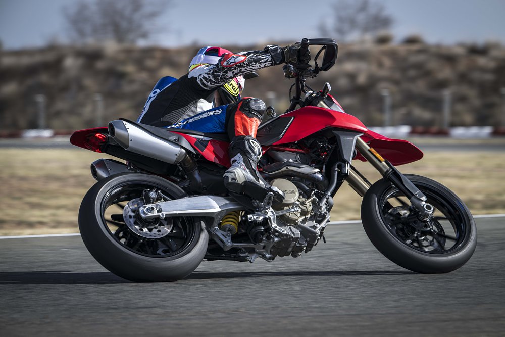 2024 Ducati Hypermotard 698 right side action showing the underside of the bike, as it rides through a left-hand corner at a race track.