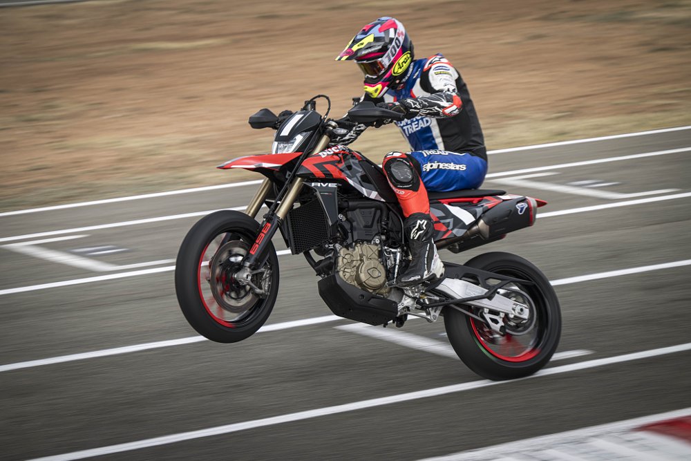 2024 Ducati Hypermotard 698 left side, doing a wheelie at a race track.