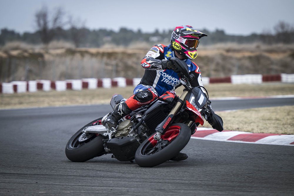 2024 Ducati Hypermotard 698 from the right side, turning through a left-hand corner at a race track.