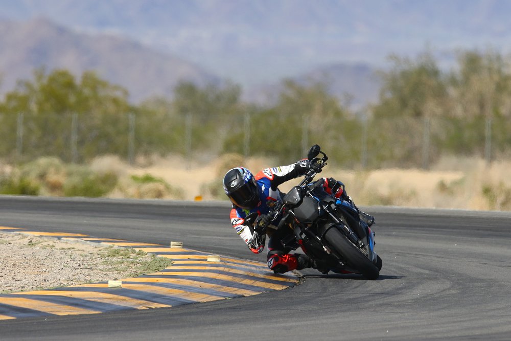 2023 BMW M 1000 R riding toward camera through a right-hand turn at a racetrack.