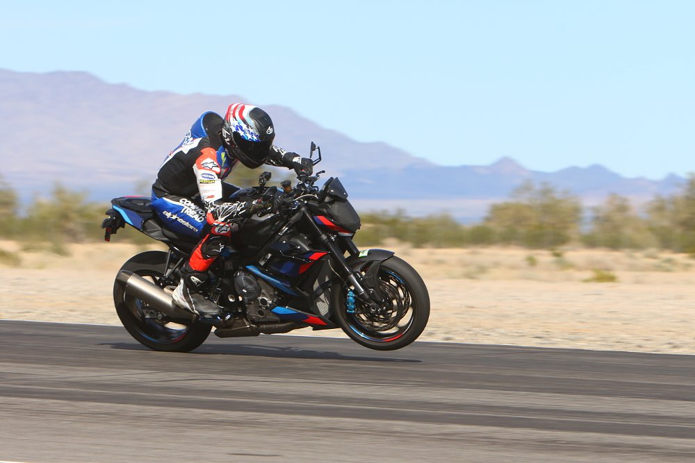2023 BMW M 1000 R riding on a racetrack doing a power wheelie.