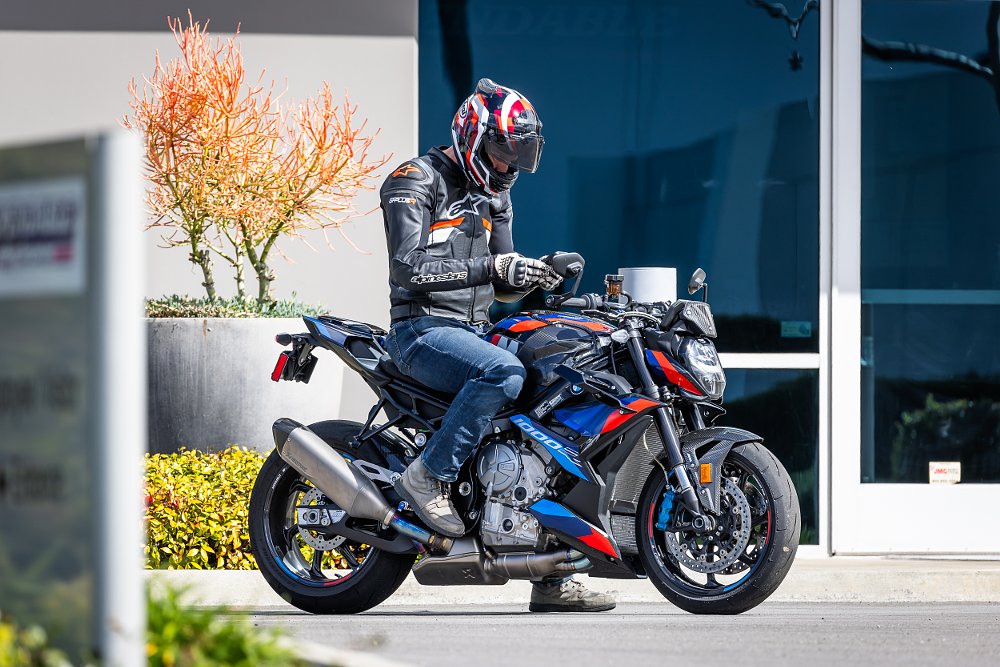 2023 BMW M 1000 R with rider on board, sitting in a parking lot.
