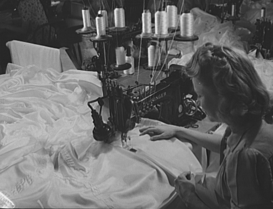black and white photo of a woman at a sewing machine
