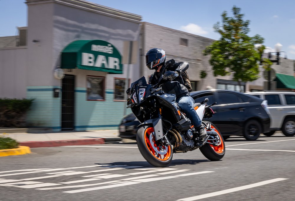 2024 KTM 890 SMT from the left, riding through a town.