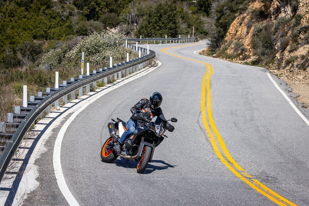 2024 KTM 890 SMT sliding into a curve on a mountain road.