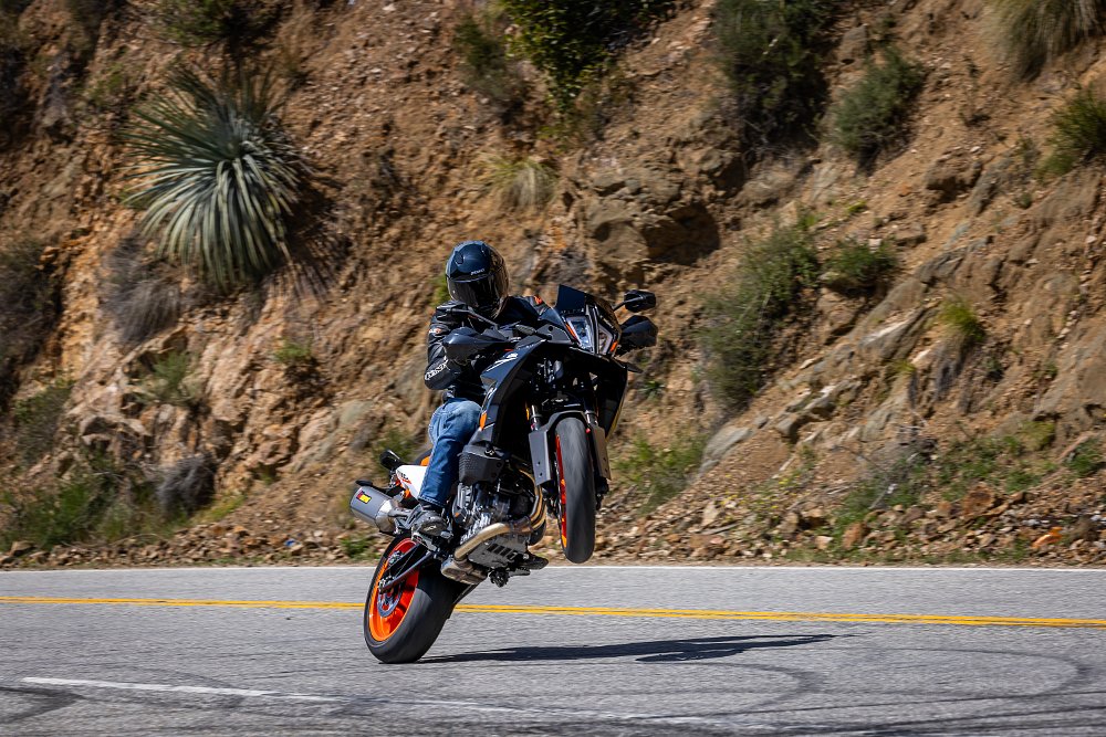 2024 KTM 890 SMT right side, doing a wheelie on a mountain road.