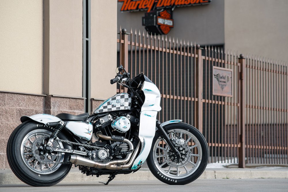 white Sportster with full fairing parked in front of a Harley-Davidson sign