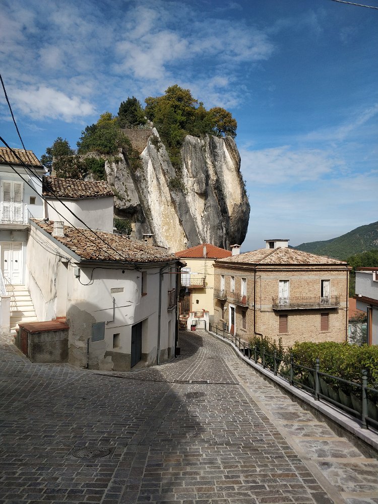 view of the huge rock looming over the town's narrow, cobblestone street