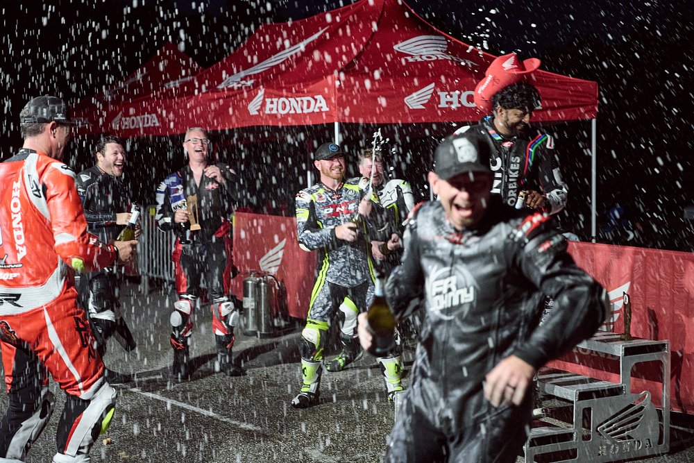 racers spraying champagne and laughing after the race