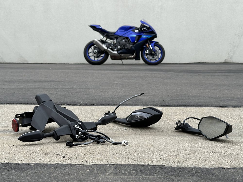 Detached blinkers and mirrors sit in the foreground, with a track-prepped 2024 Yamaha R1 in the background.