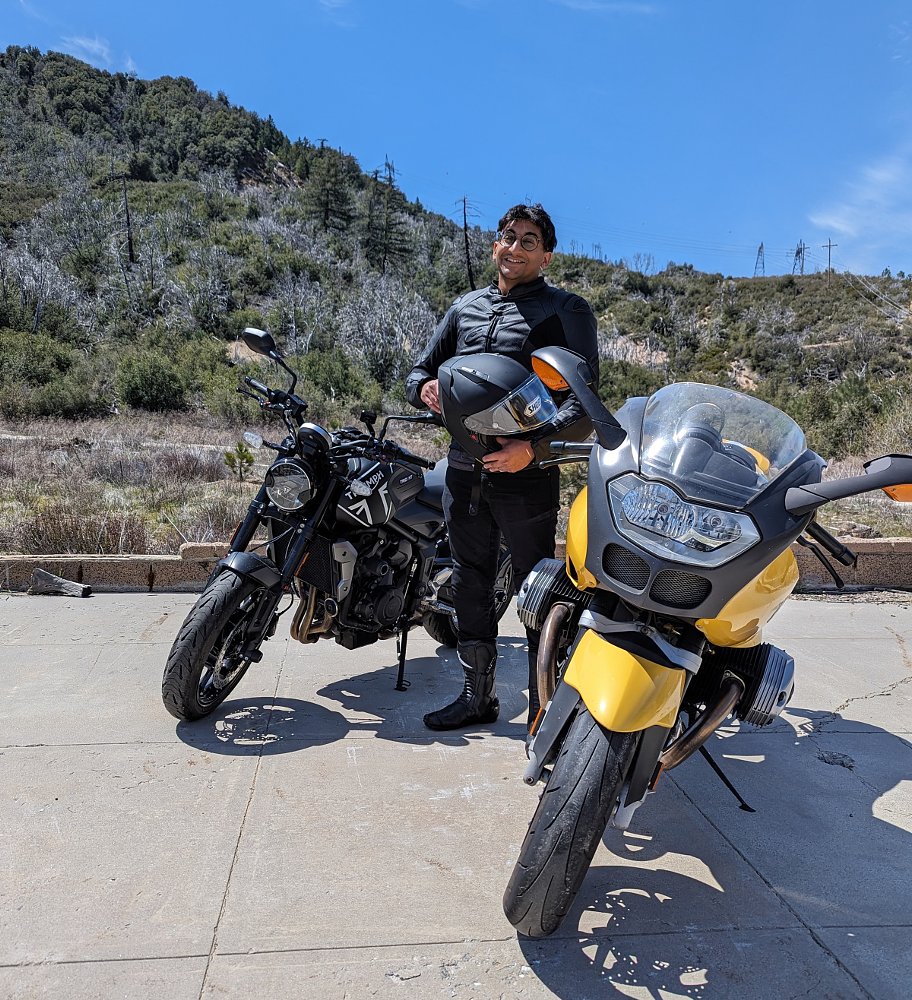 rider standing at an overlook beside two motorcycles