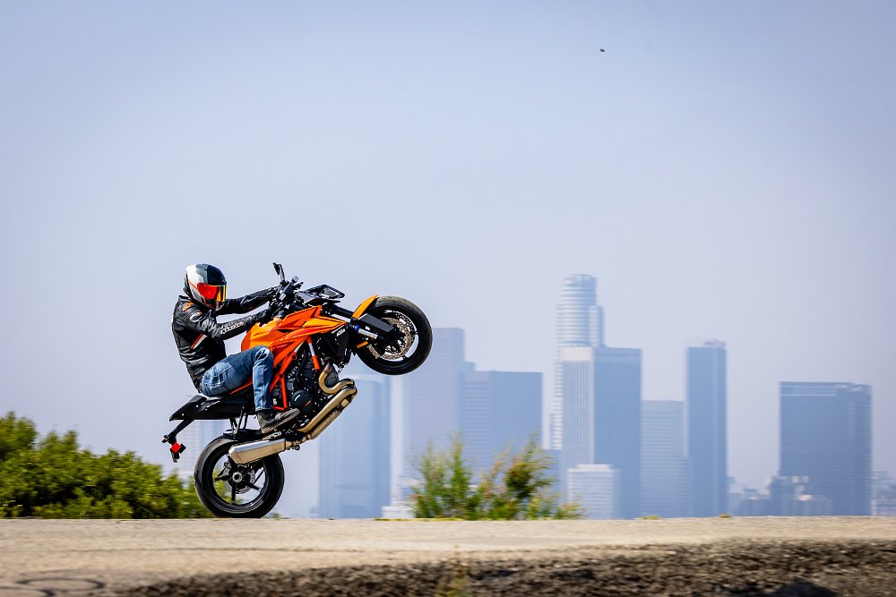 A KTM 1390 Super Duke R doing a wheelie with downtown Los Angeles in the background.