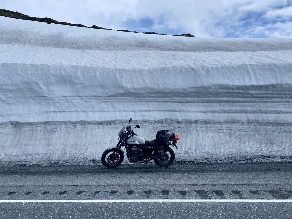 motorcycle parked in front of 20-foot-high wall of snow
