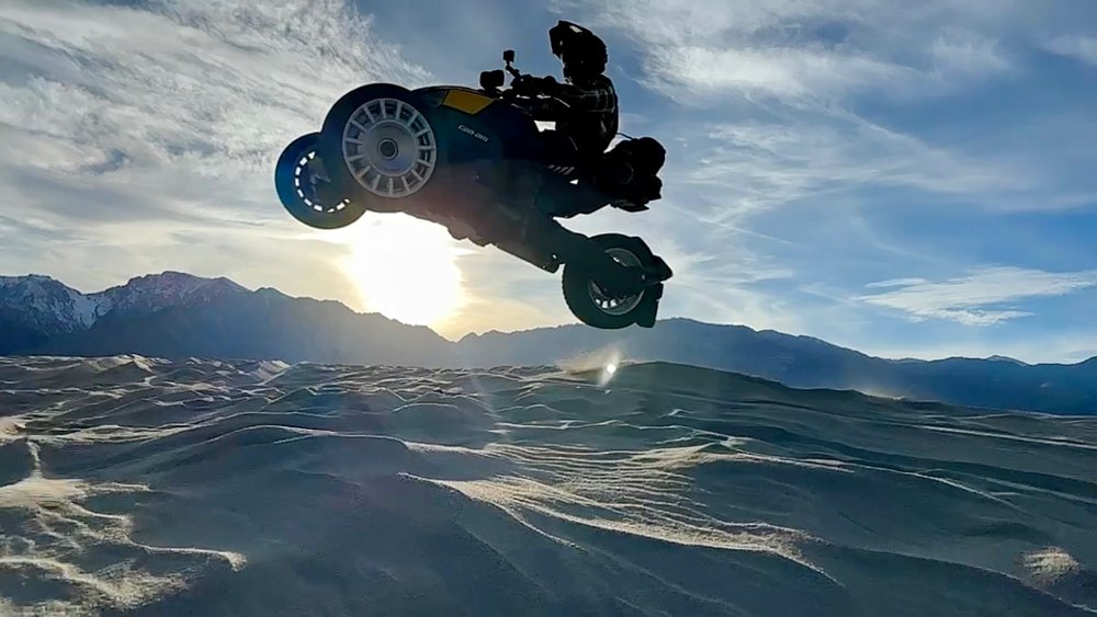 A Can-Am Ryker Rally jumping over a sand dune.